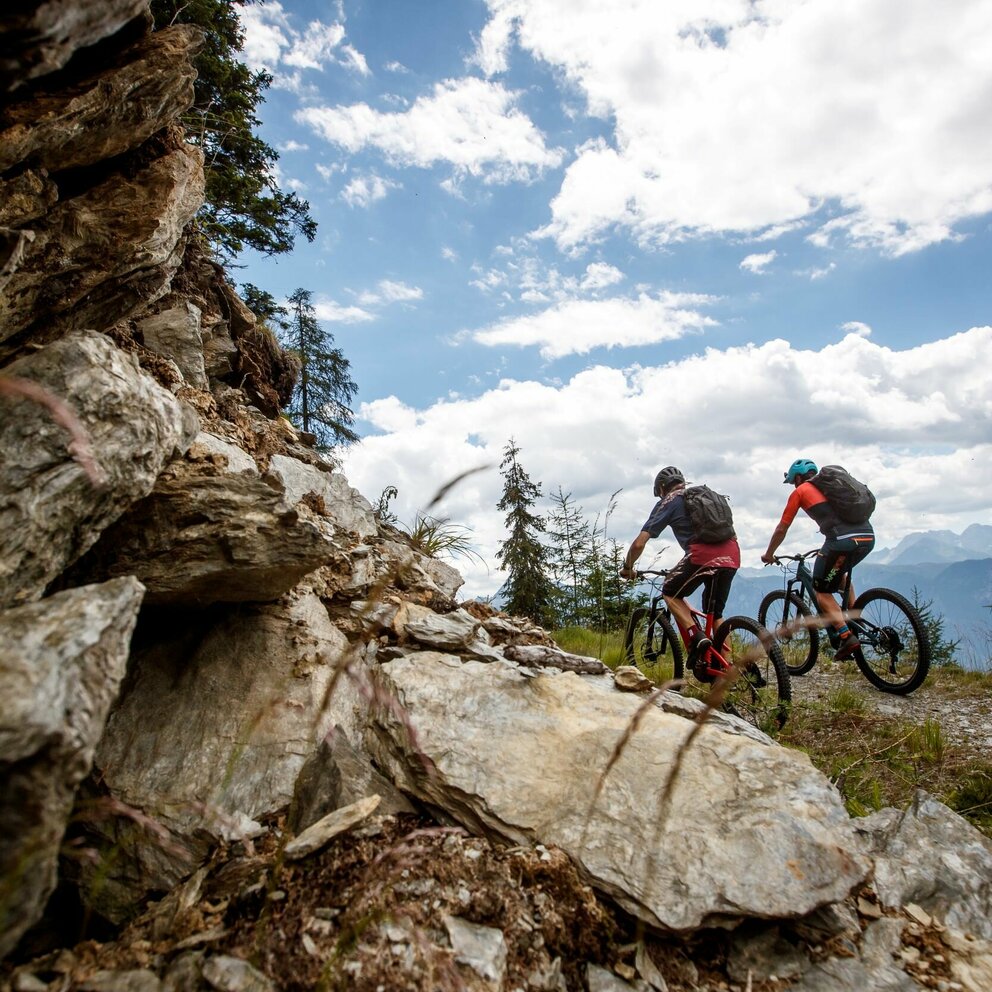Zwei Radfahrer auf einem schmalen Weg auf der Compedalrunde im Kristeinertal. Im Vordergrund eine felsige Wand.