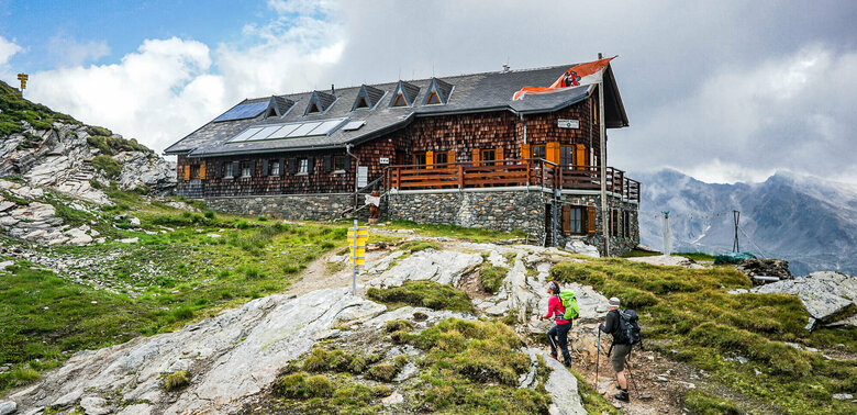 Badener Huette am Adlerweg Osttirol Etappe 4 Zwei Personen mit Wanderstöcken auf den letzten Metern vor der Badener Huette am Adlerweg in Osttirol.
