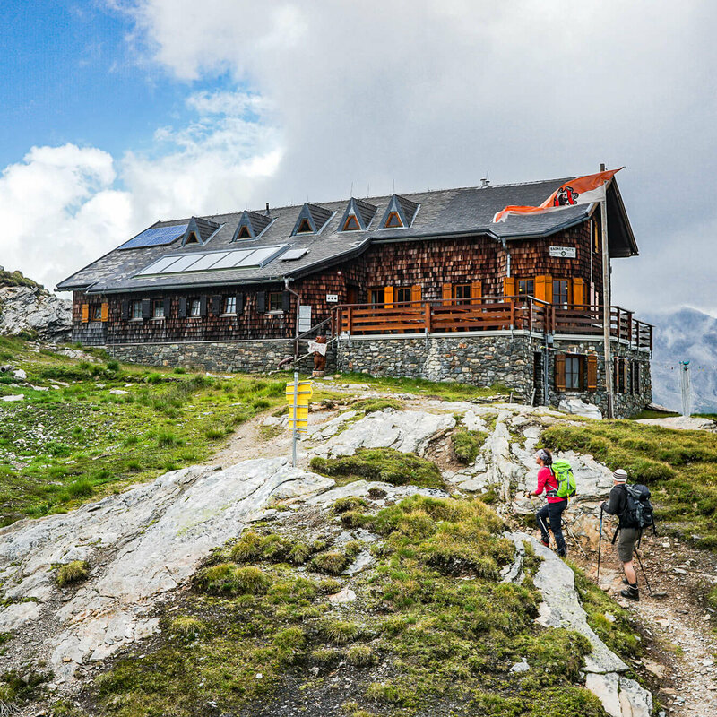 Badener Huette am Adlerweg Osttirol Etappe 4 Zwei Personen mit Wanderstöcken auf den letzten Metern vor der Badener Huette am Adlerweg in Osttirol.