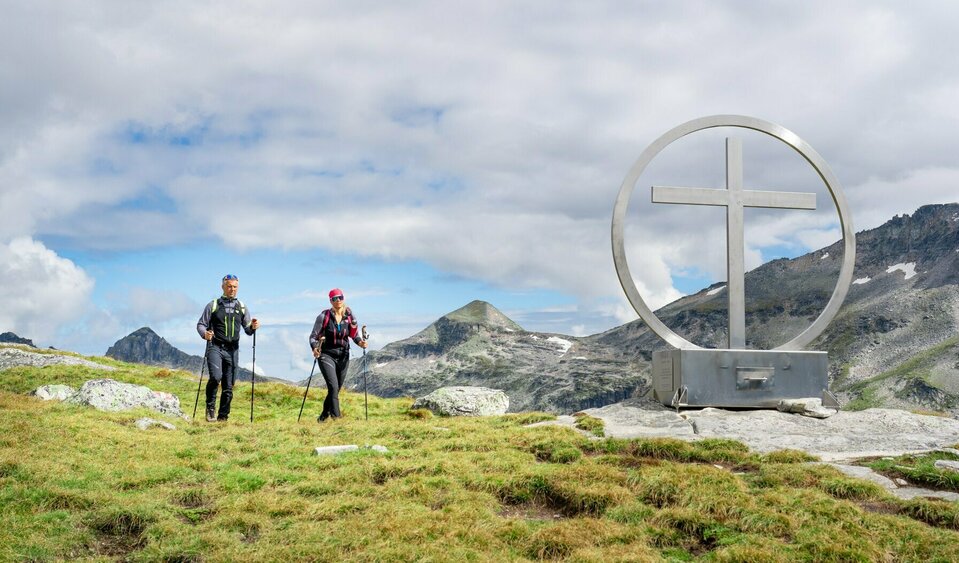 Gipfelkreuz Spinewitrol Weitwandern auf der Glocknerkrone in Osttirol, Etappe 2: Wanderer am Gipfelkreuz Spinewitrol mit Blick nach Norden auf den Medelzkopf nahe Kals am Großglockner.